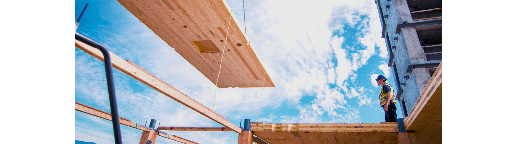 Construction working monitoring mass timber being lifted.