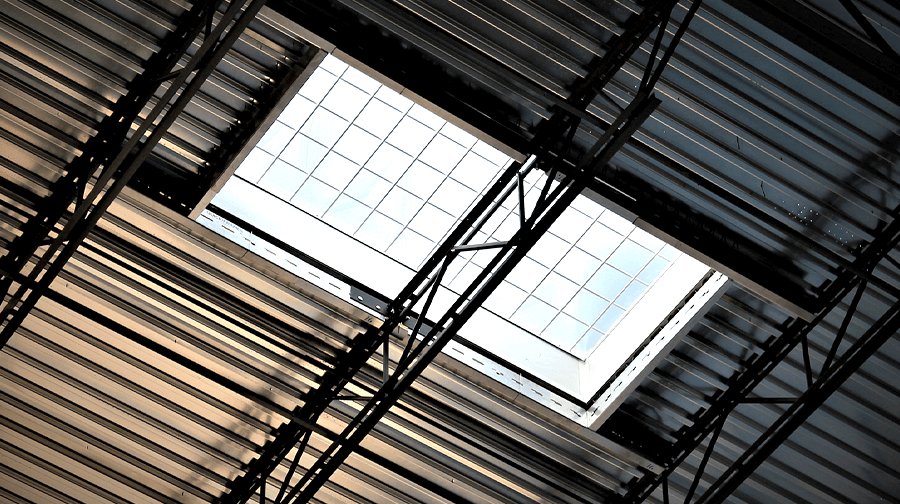 A skylight framed within a metal roof structure, allowing natural light to enter the building through the corrugated steel decking.