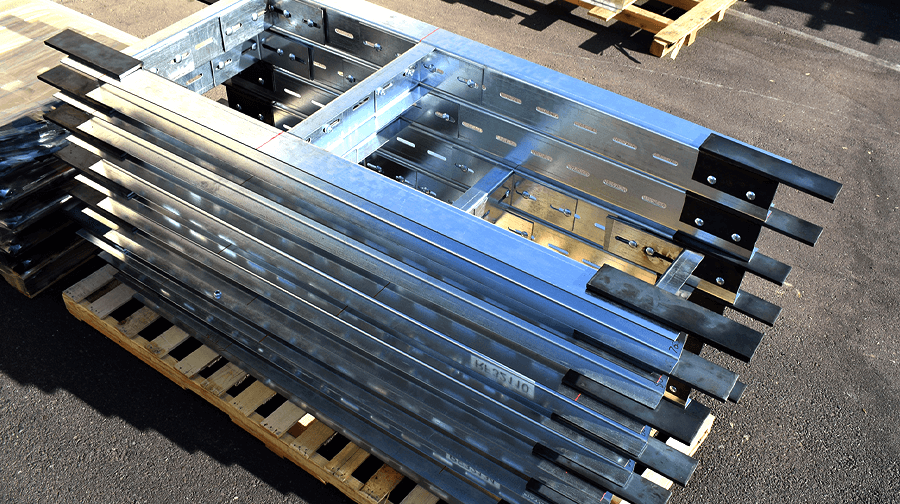 A set of galvanized steel QuickFrames components neatly stacked on a pallet, ready for installation at a construction site.